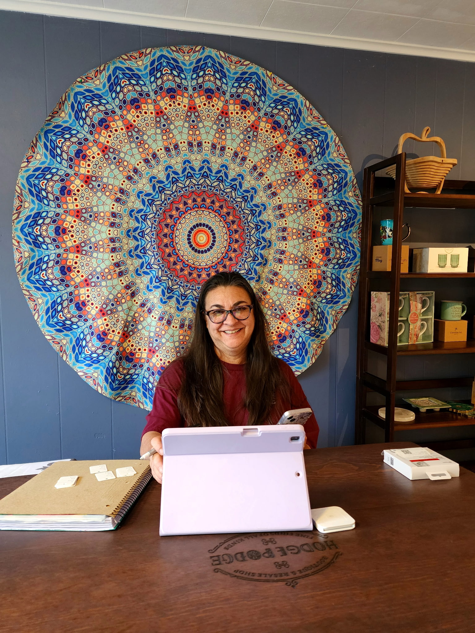 The owner of Hodgepodge with a colorful mandala on the wall